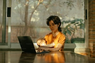 a woman holding a baby while using a laptop