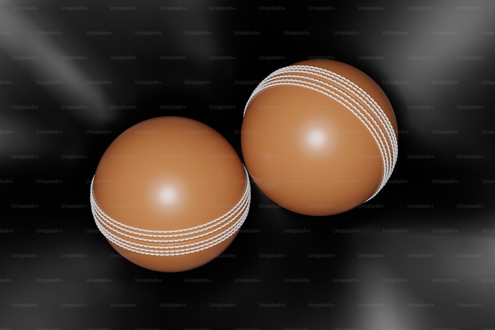 two brown leather cricket balls on a black background