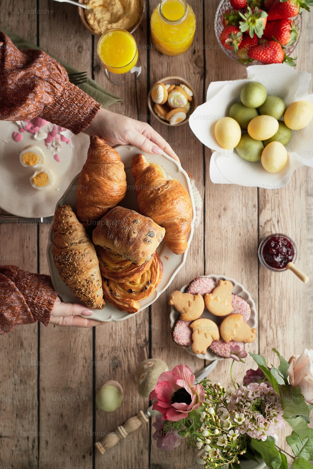 a person holding a plate of croissants and pastries