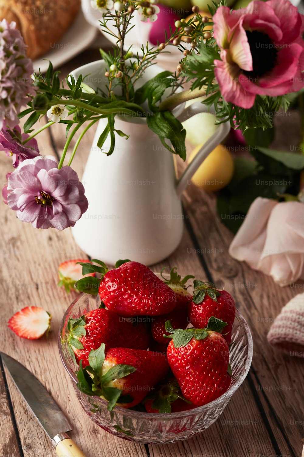 a bowl of strawberries on a wooden table