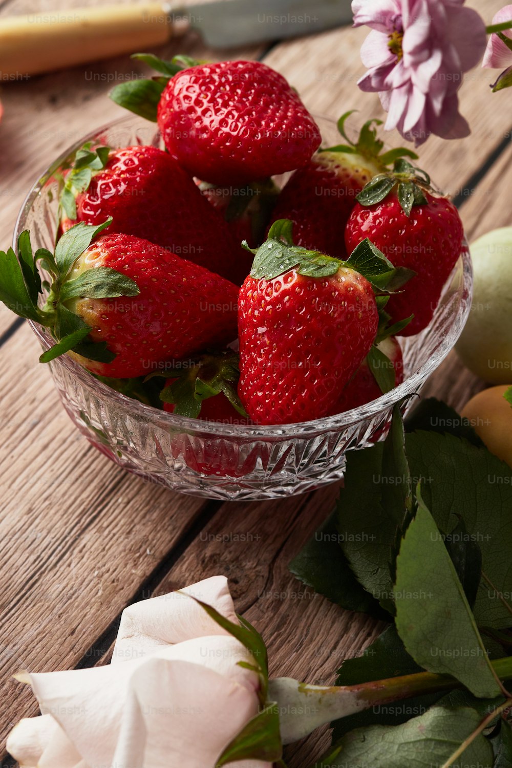 a glass bowl filled with strawberries on top of a wooden table
