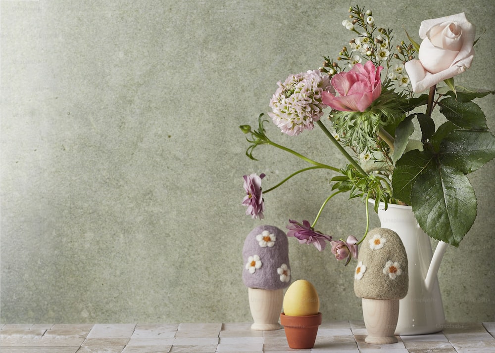 eine Vase gefüllt mit Blumen neben zwei kleinen Steinen