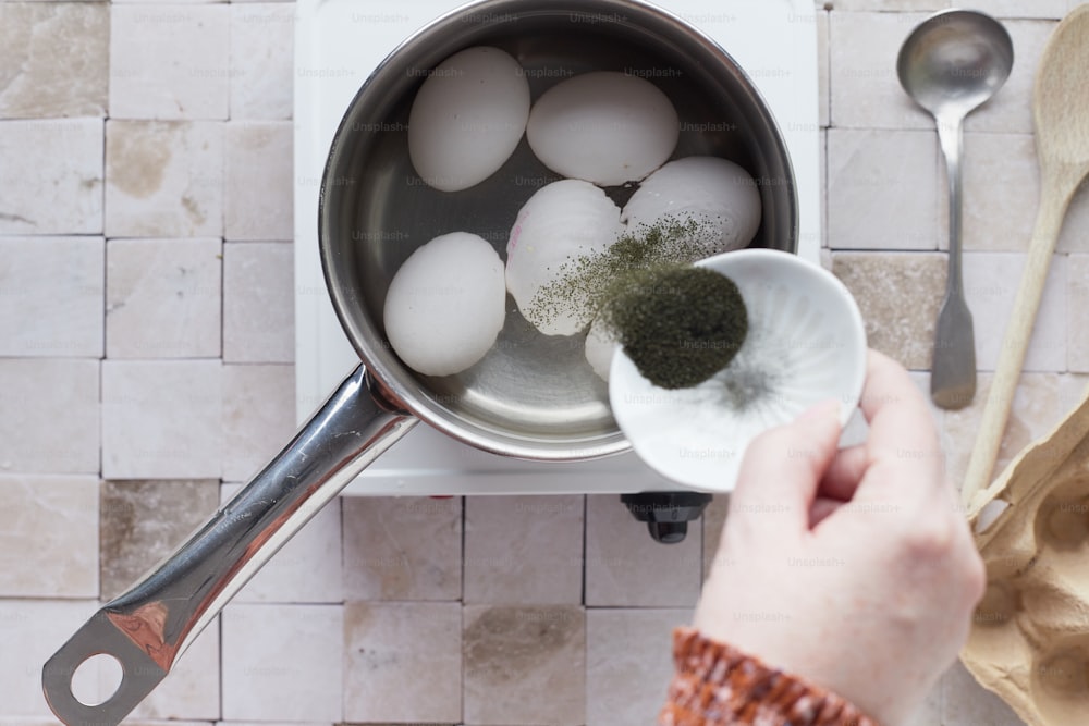 a person holding a spoon over a pot of eggs
