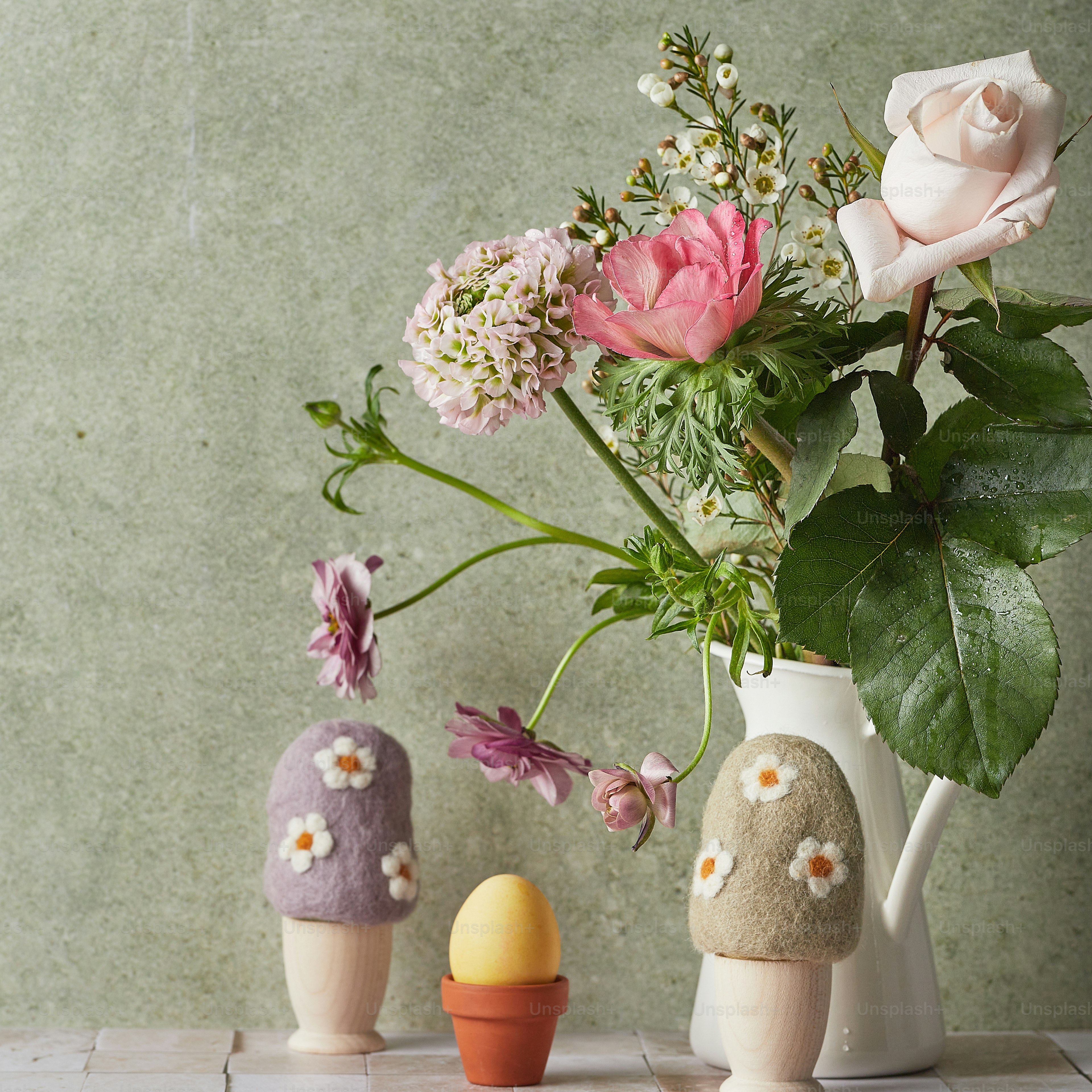 a vase filled with flowers next to a couple of eggs