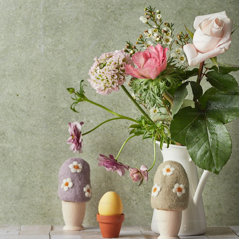 a vase filled with flowers next to a couple of eggs