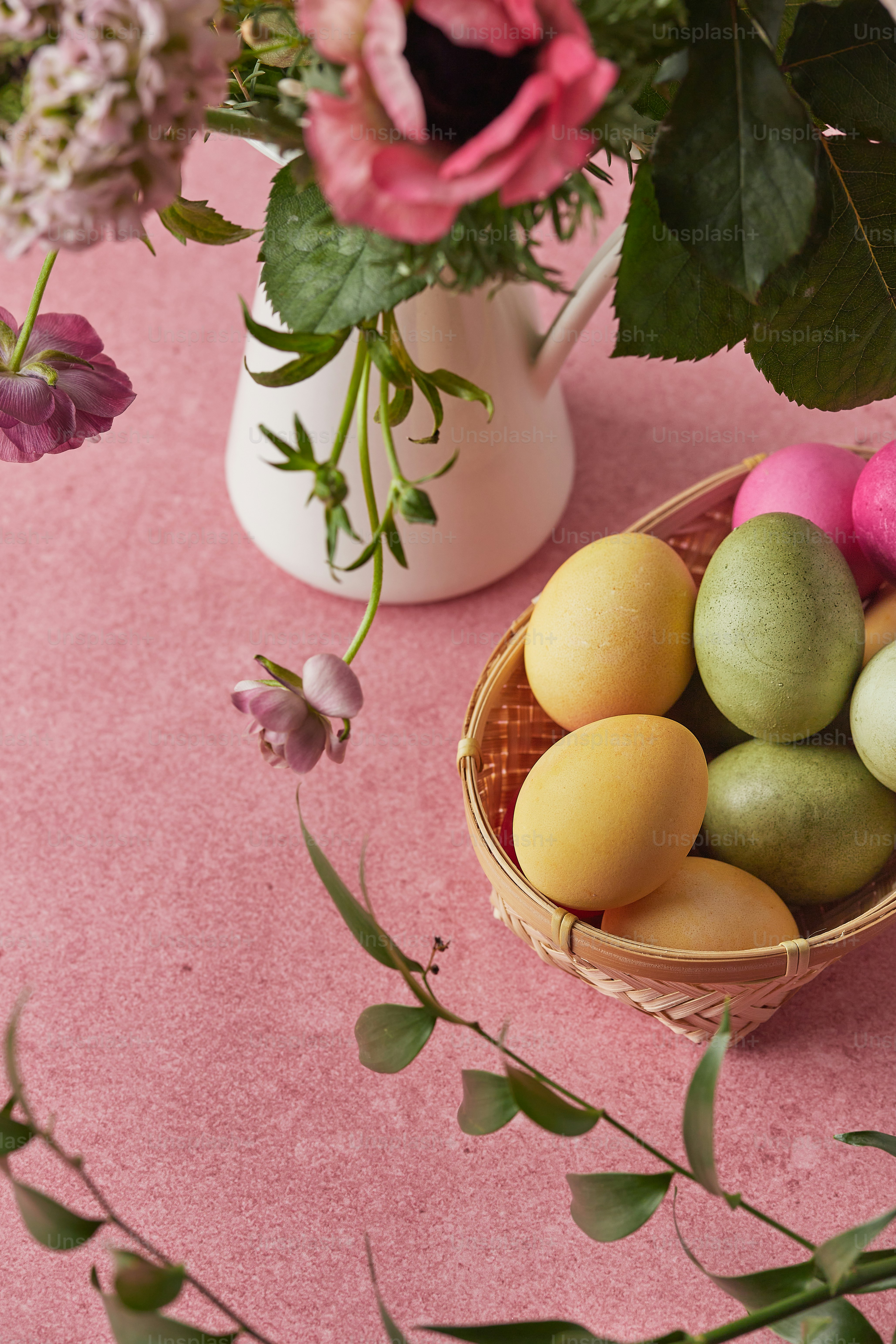 a basket of eggs sitting on a table next to a vase of flowers