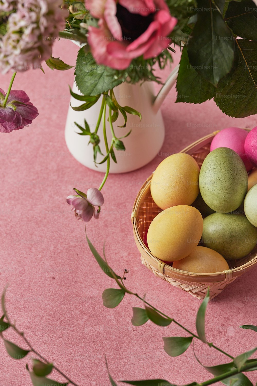 Una canasta de huevos sentada en una mesa junto a un jarrón de flores