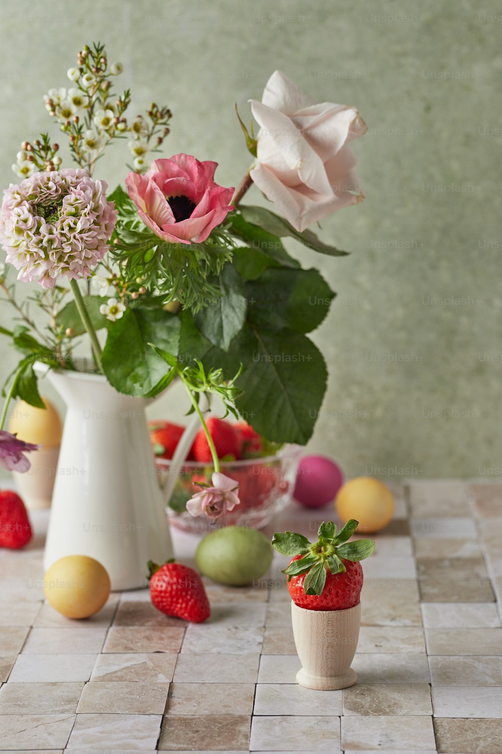 Un jarrón blanco lleno de flores y frutas