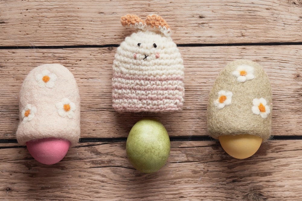 a group of three knitted eggs sitting on top of a wooden table