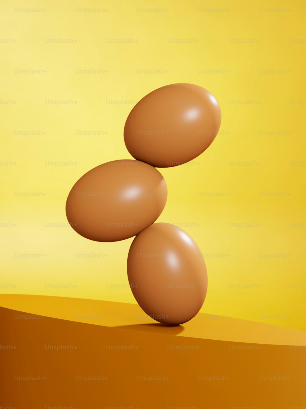 three eggs balancing on top of each other on a yellow background