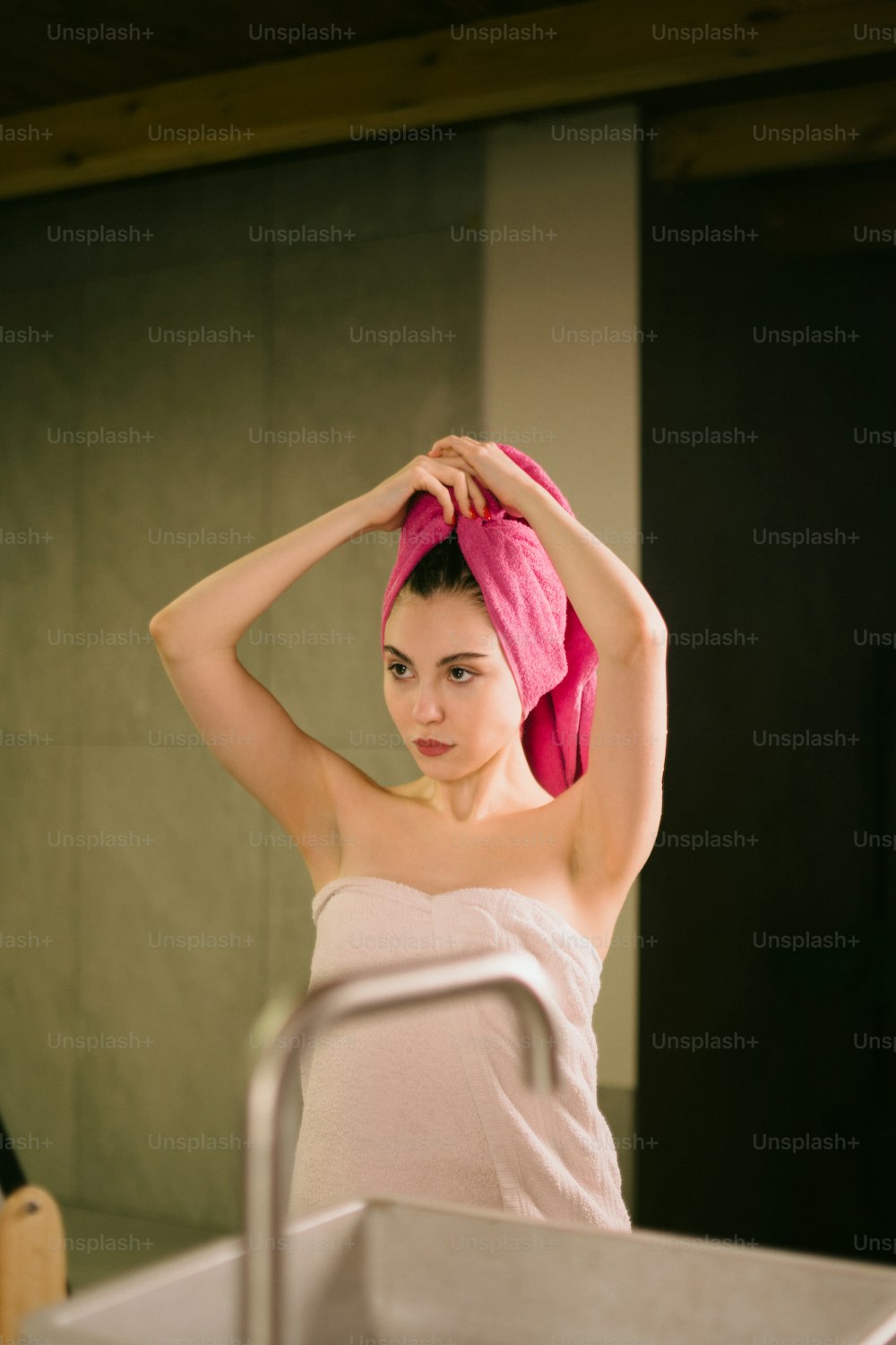 uma mulher com uma toalha na cabeça em uma sala de banho