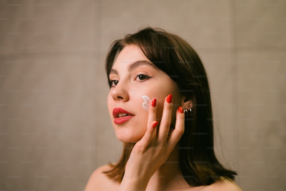 a woman with red nail polish holding her hand up to her face