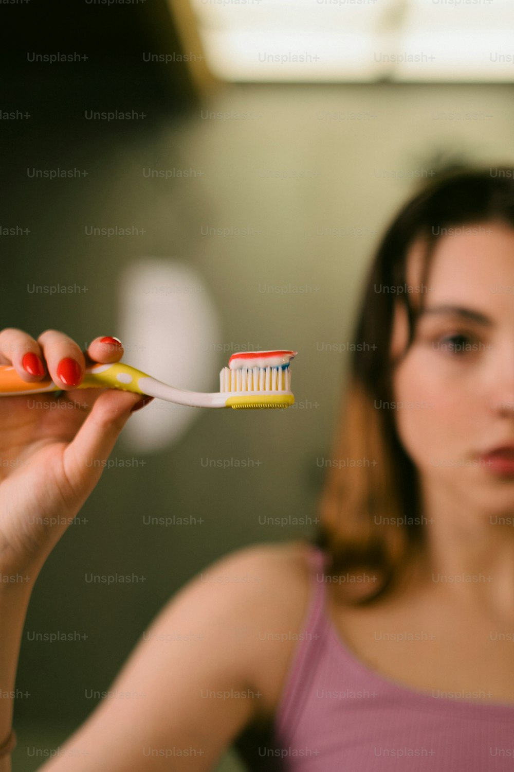a woman holding a toothbrush with a toothpaste on it
