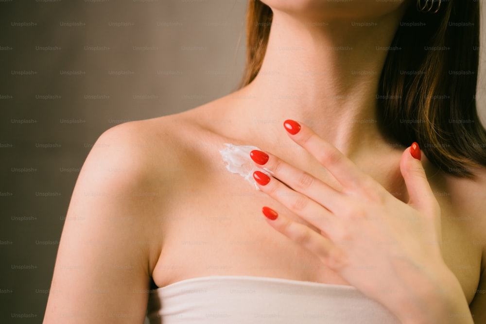 a woman with red nail polish holding her hand up to her chest