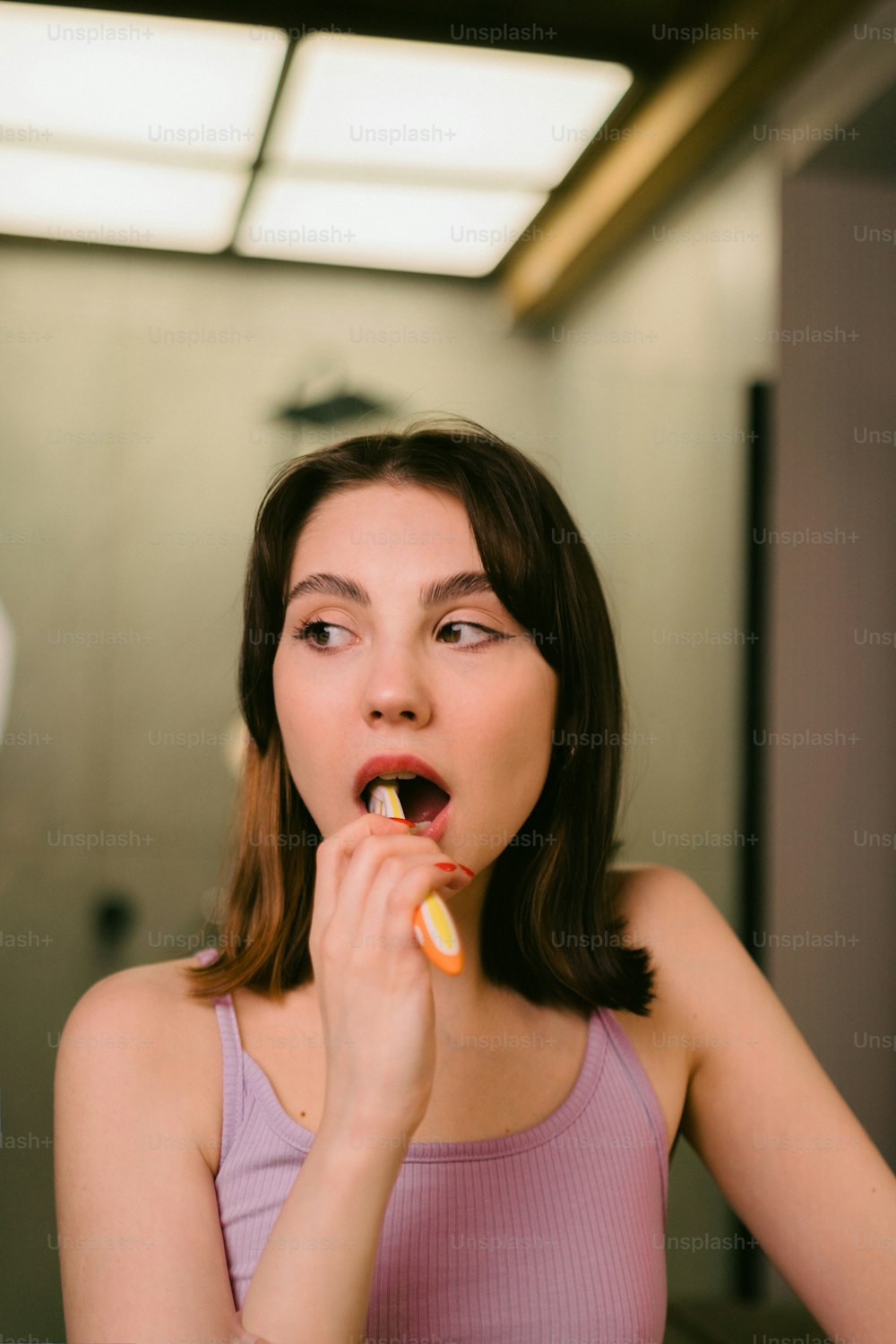 a woman is brushing her teeth in the bathroom