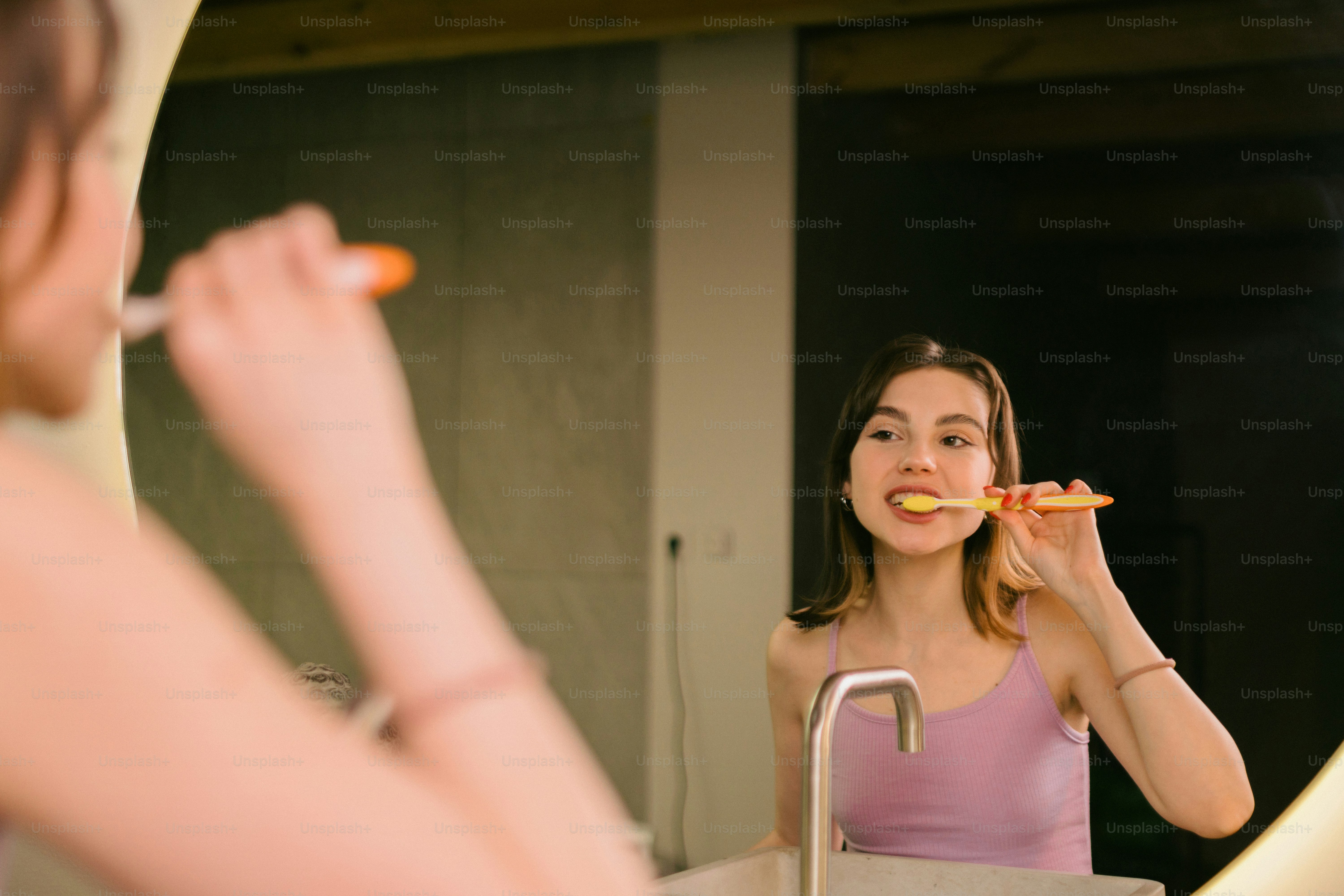 a woman brushing her teeth in front of a mirror