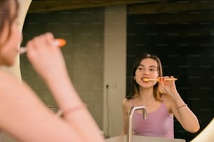Une femme se brossant les dents devant un miroir