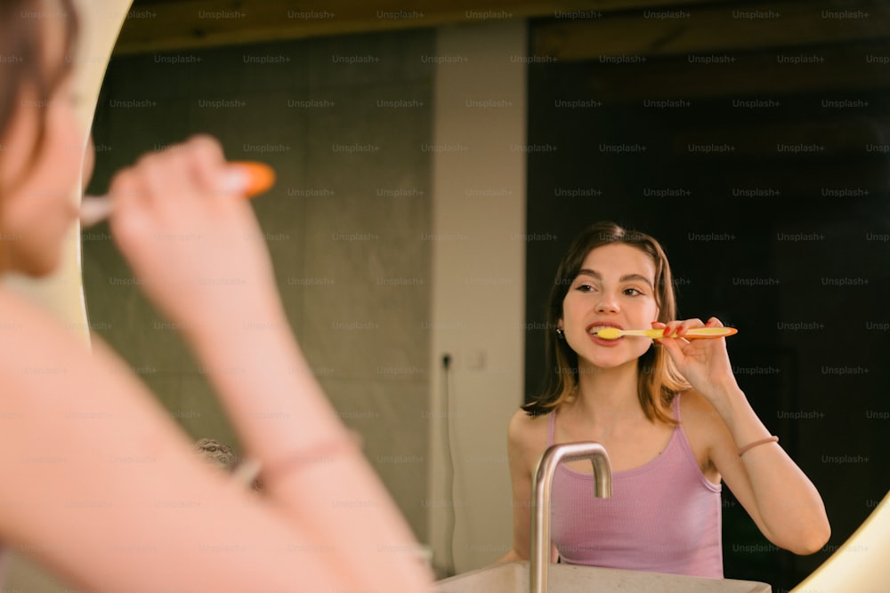 Una mujer cepillándose los dientes frente a un espejo