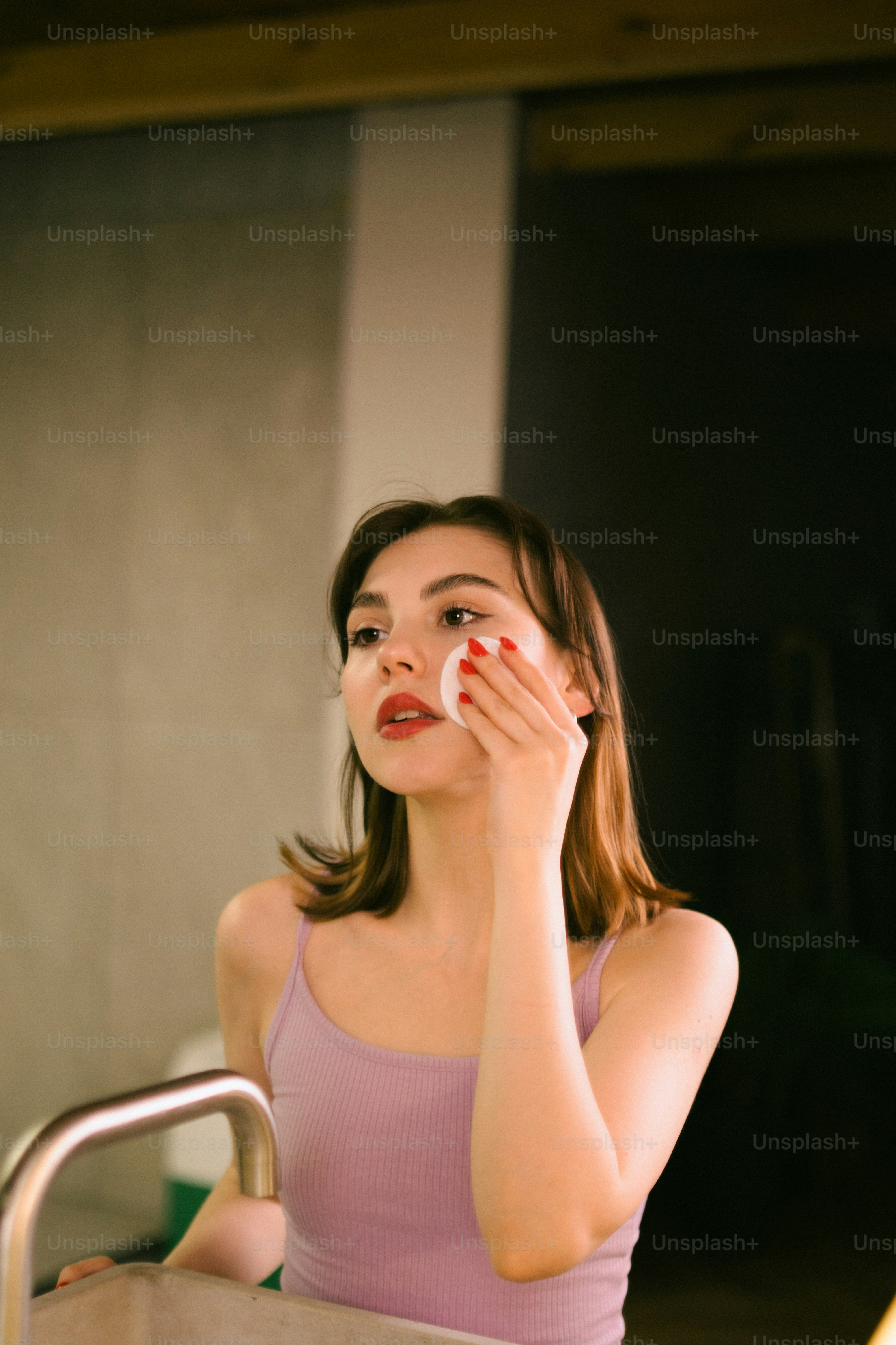 Eine Frau in einem Tanktop hält ihre Hand vor ihr Gesicht