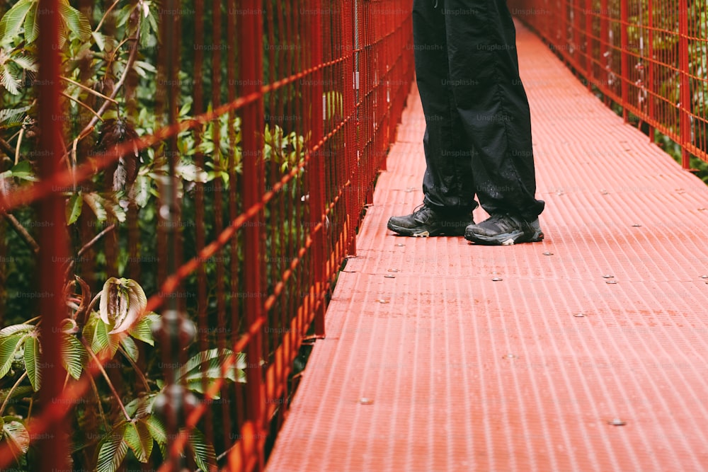 uma pessoa andando através de uma ponte vermelha sobre a água