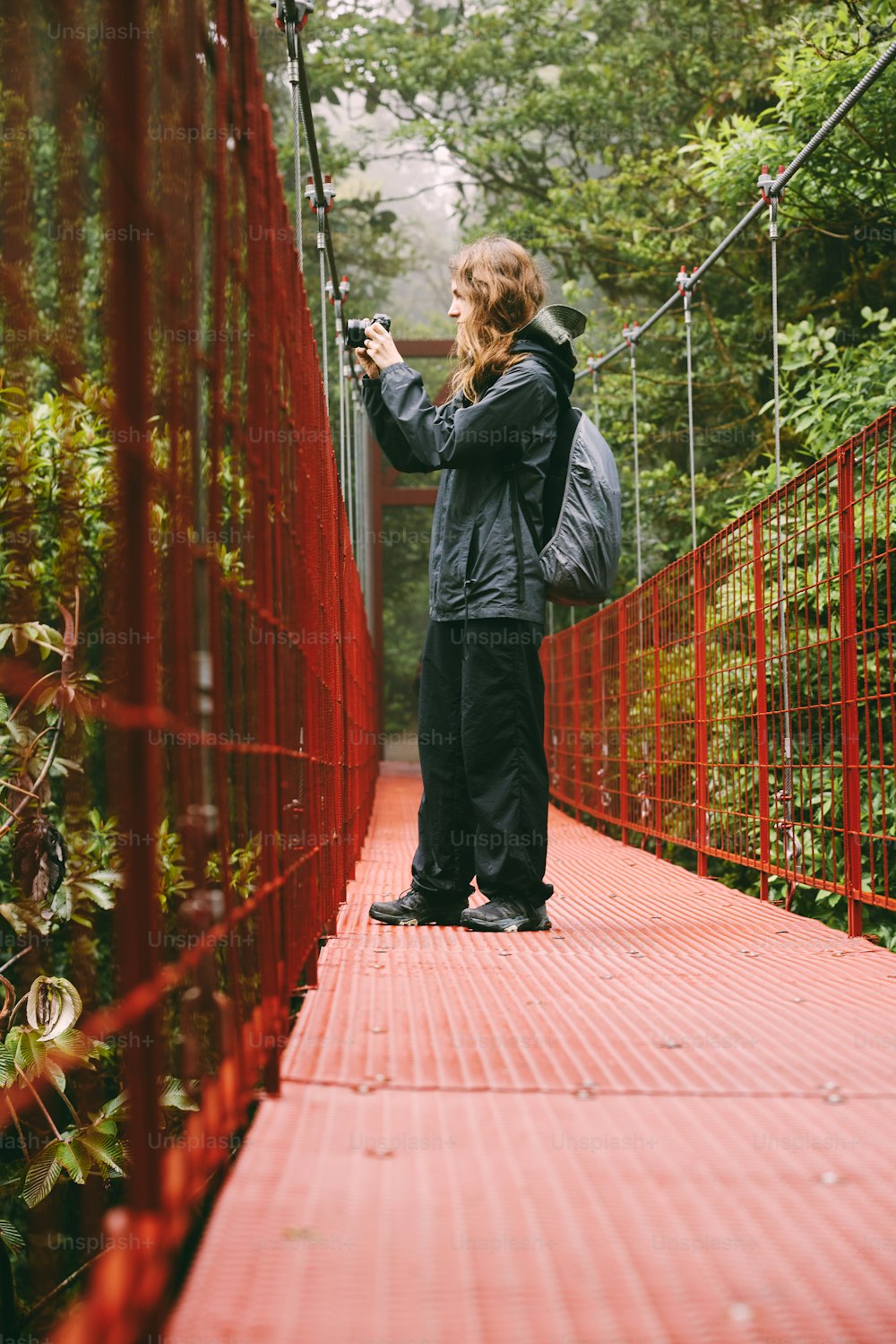a woman standing on a red bridge taking a picture