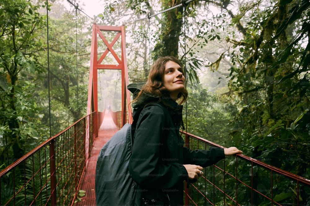a woman standing on a bridge in the middle of a forest