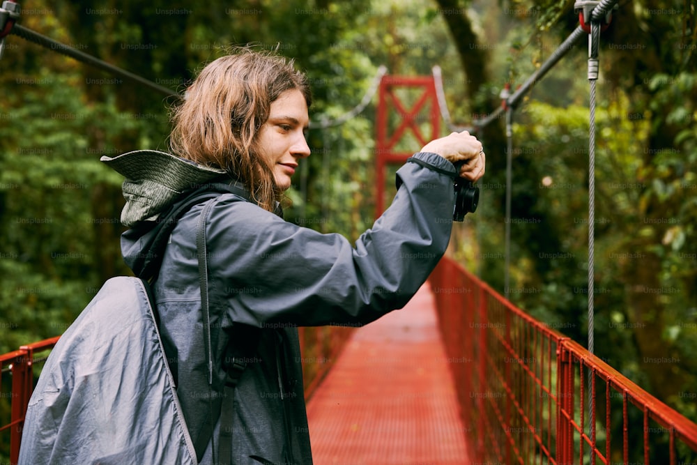 a man standing on a red suspension bridge