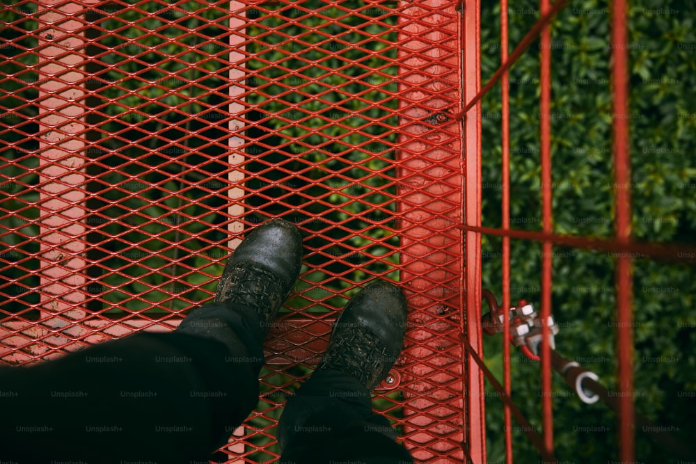 a person standing in front of a red fence