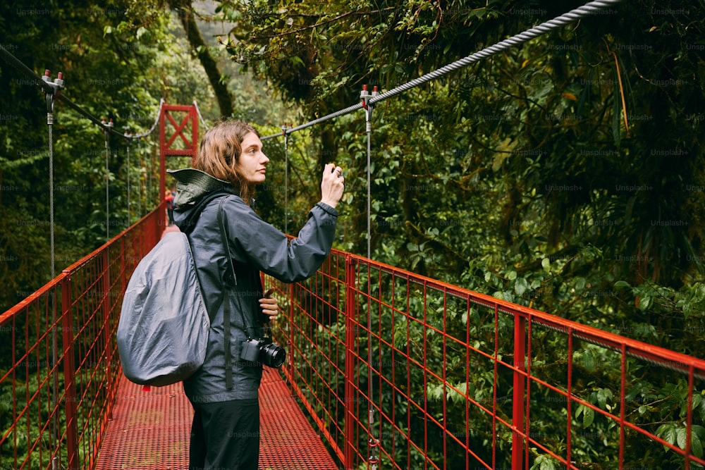 uma mulher em pé em uma ponte vermelha tirando uma foto