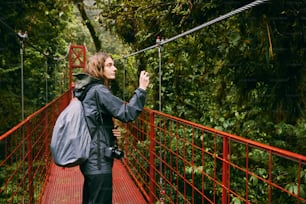 a woman standing on a red bridge taking a picture