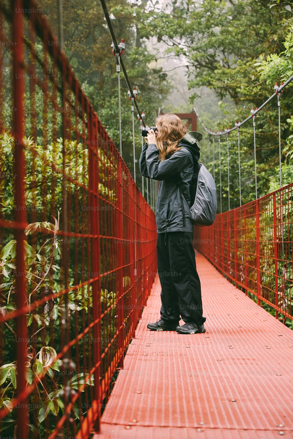Una persona in piedi su un ponte rosso con una macchina fotografica