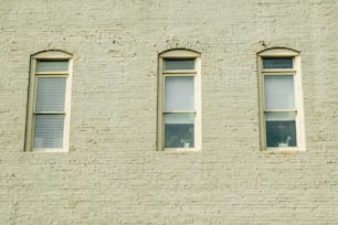 three windows on the side of a brick building