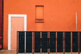 a red building with a white door and a black fence