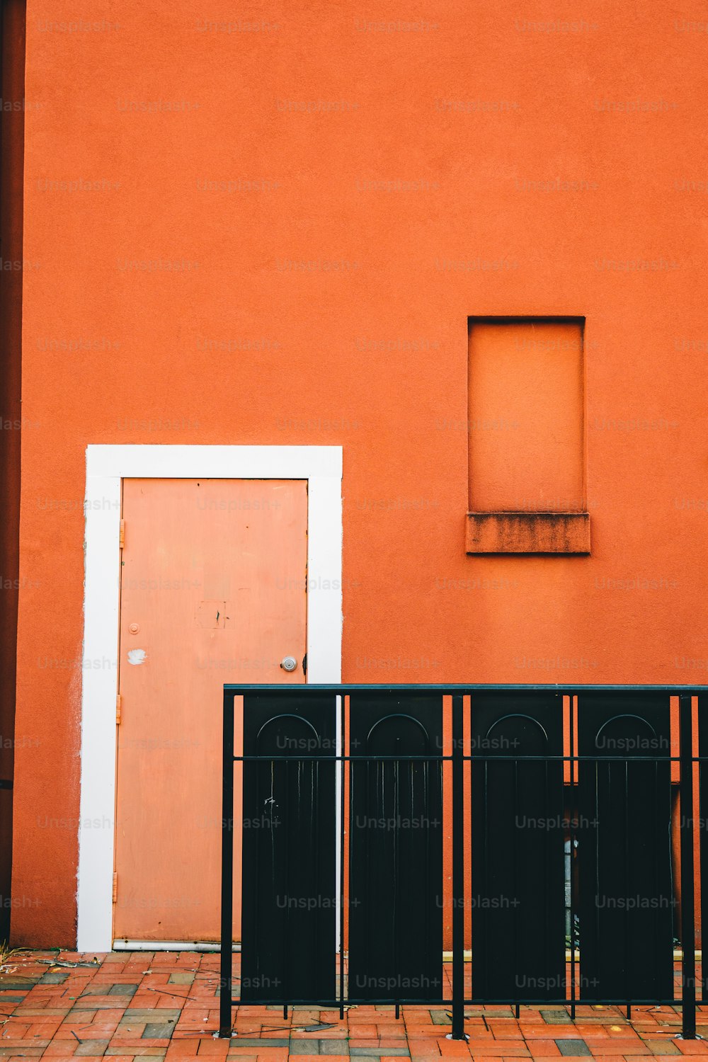 a red building with a white door and a black fence