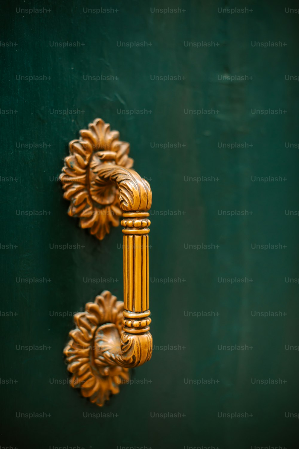 a golden door handle on a green door