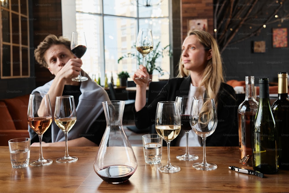 um homem e uma mulher sentados em uma mesa com taças de vinho
