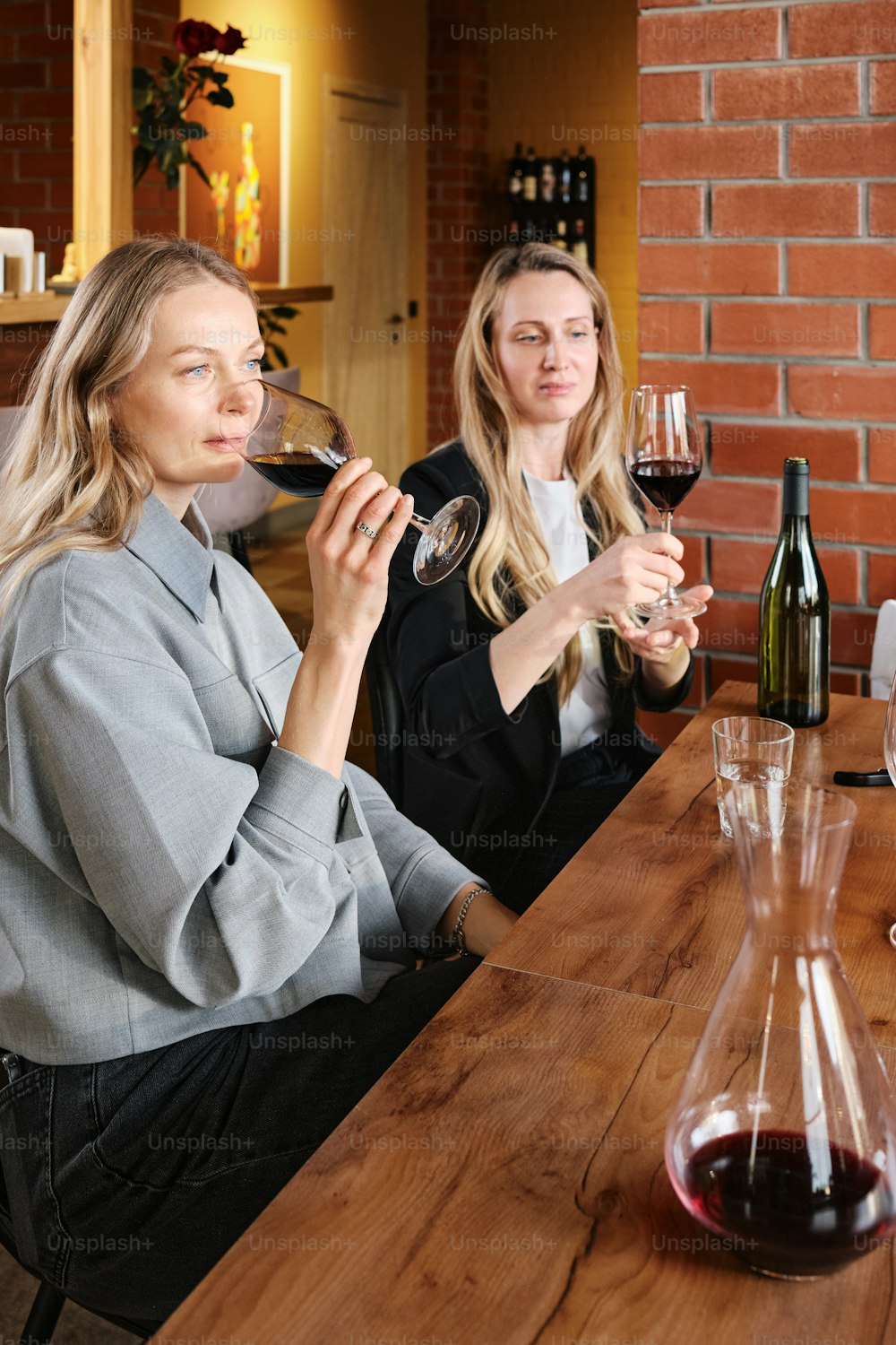 two women sitting at a table drinking wine