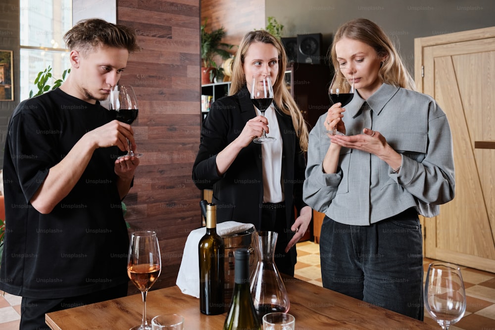 um grupo de pessoas em pé ao redor de uma mesa com taças de vinho