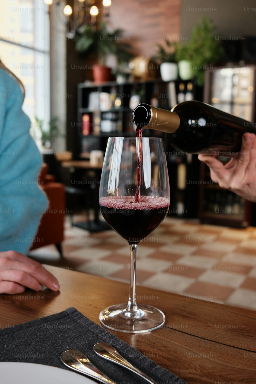 eine Person, die Rotwein in ein Weinglas gießt
