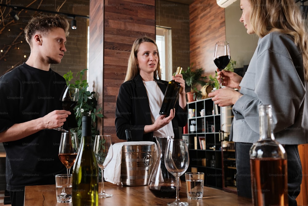 um grupo de pessoas em pé ao redor de uma mesa com taças de vinho