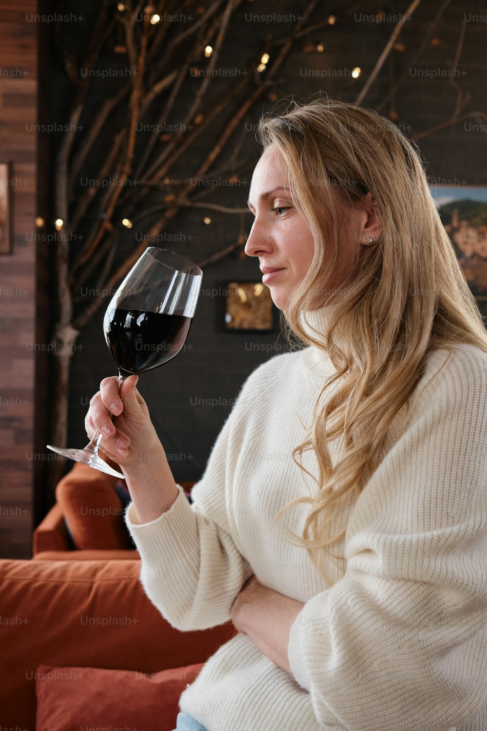 a woman sitting on a couch holding a glass of wine