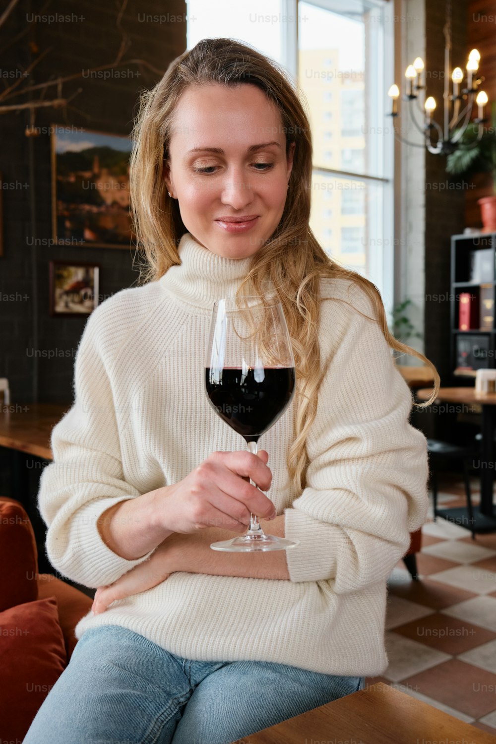 una donna seduta a un tavolo con in mano un bicchiere di vino
