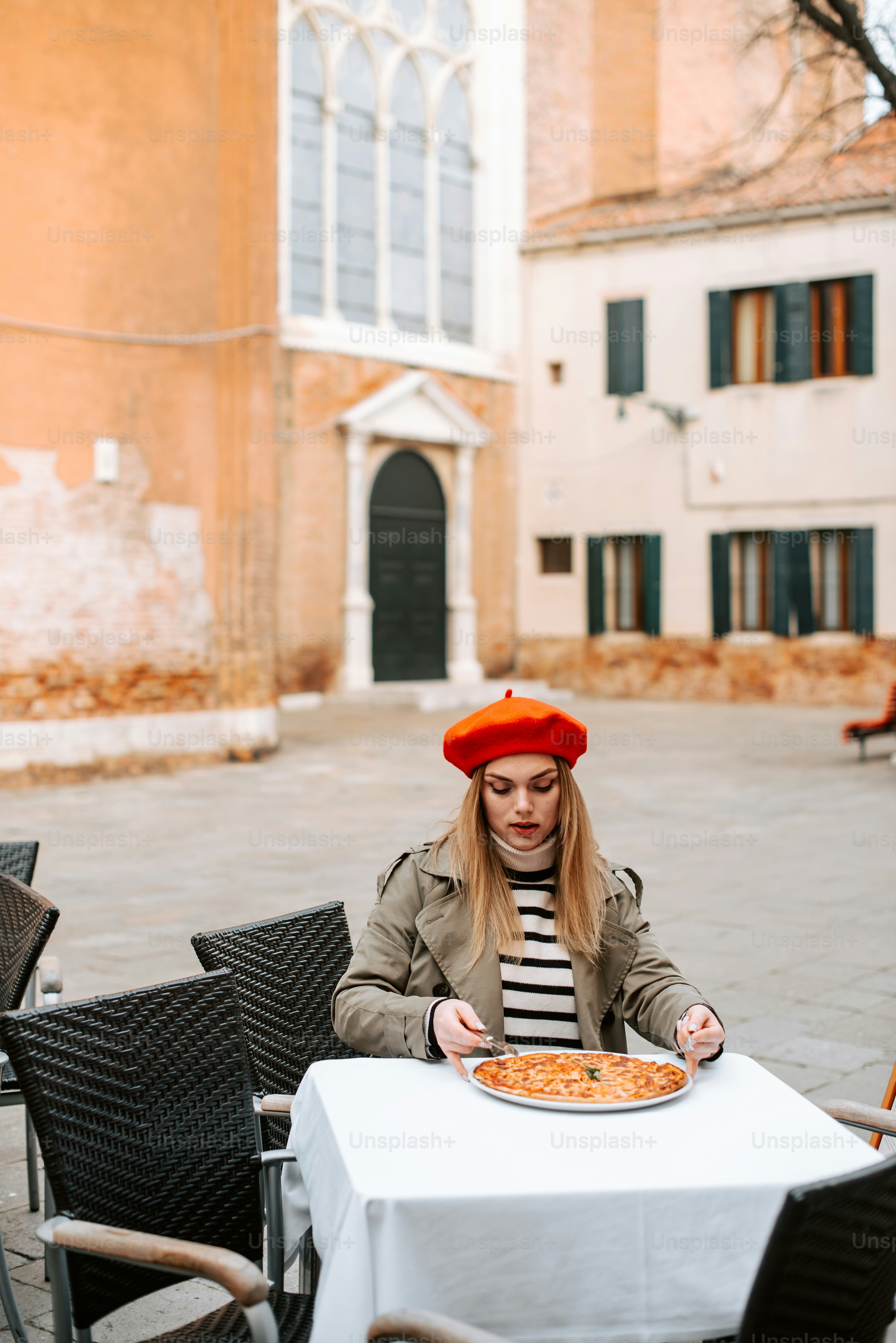 a woman sitting at a table with a pizza in front of her