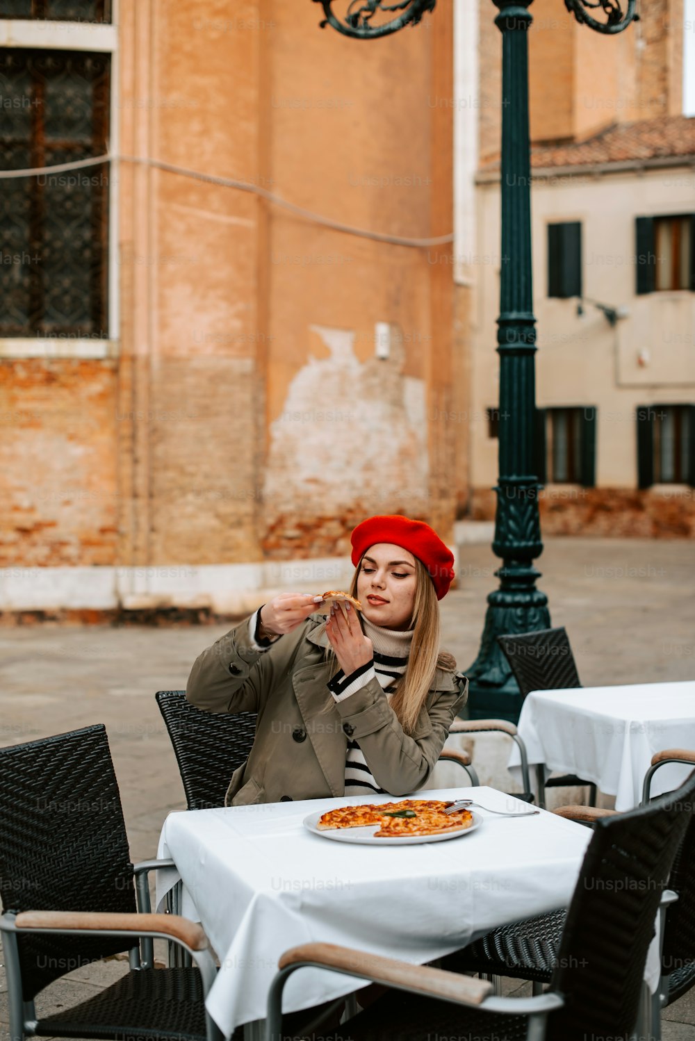 Eine Frau sitzt an einem Tisch mit einem Teller Pizza