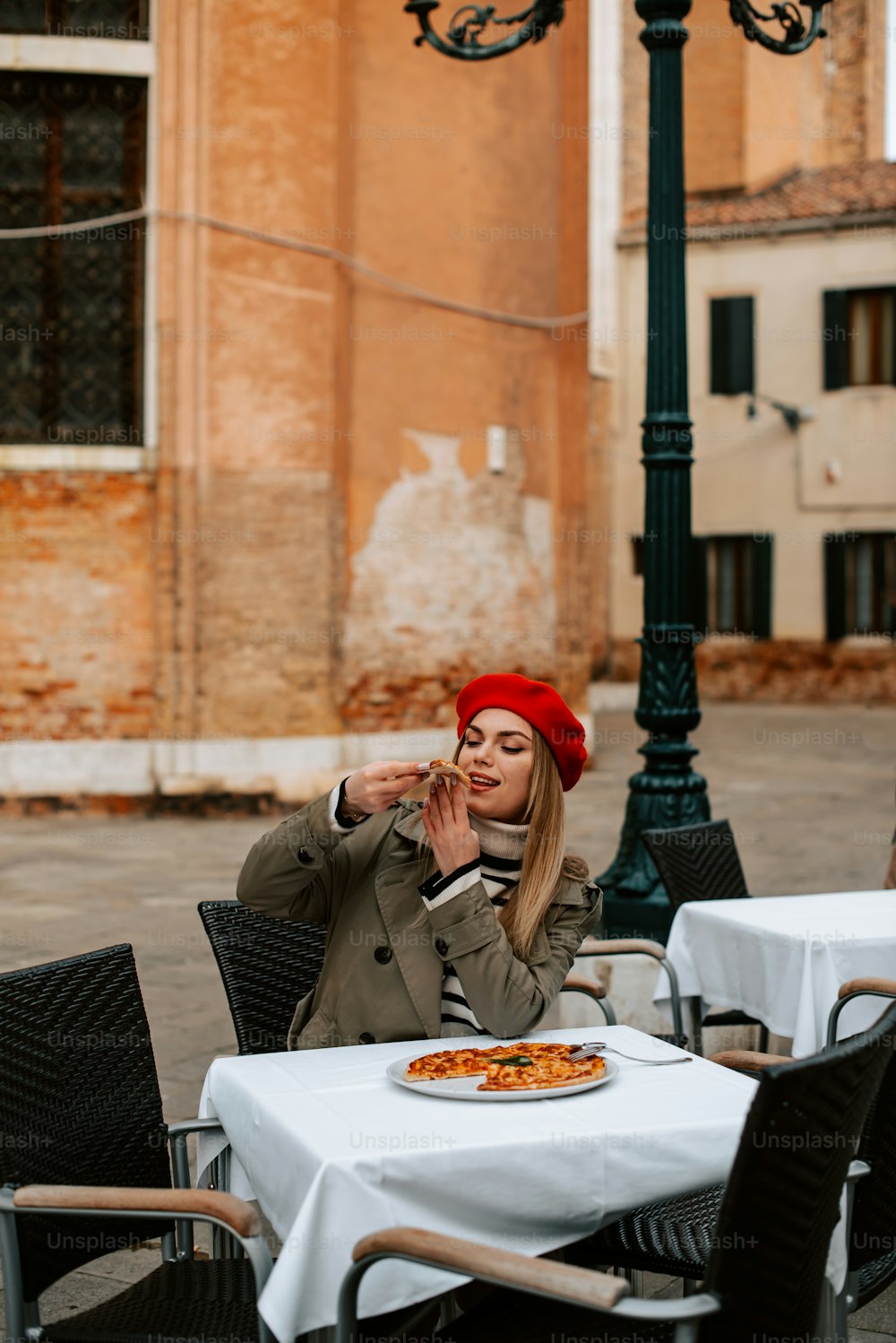 Una mujer sentada en una mesa con una pizza frente a ella
