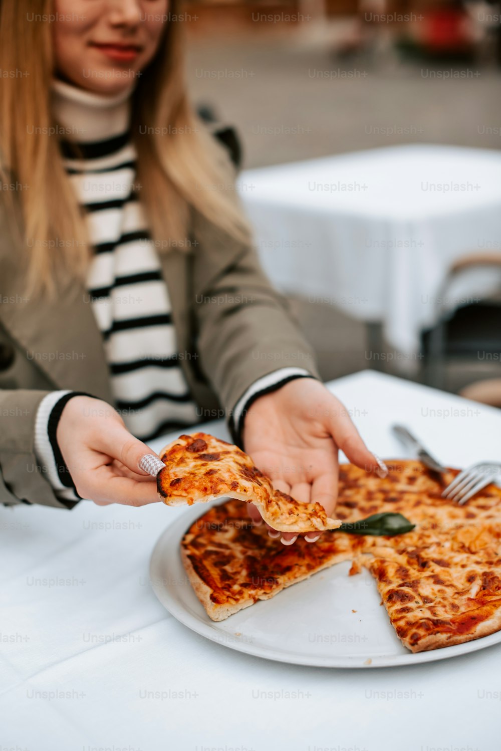 a woman cutting a slice of pizza with a knife and fork