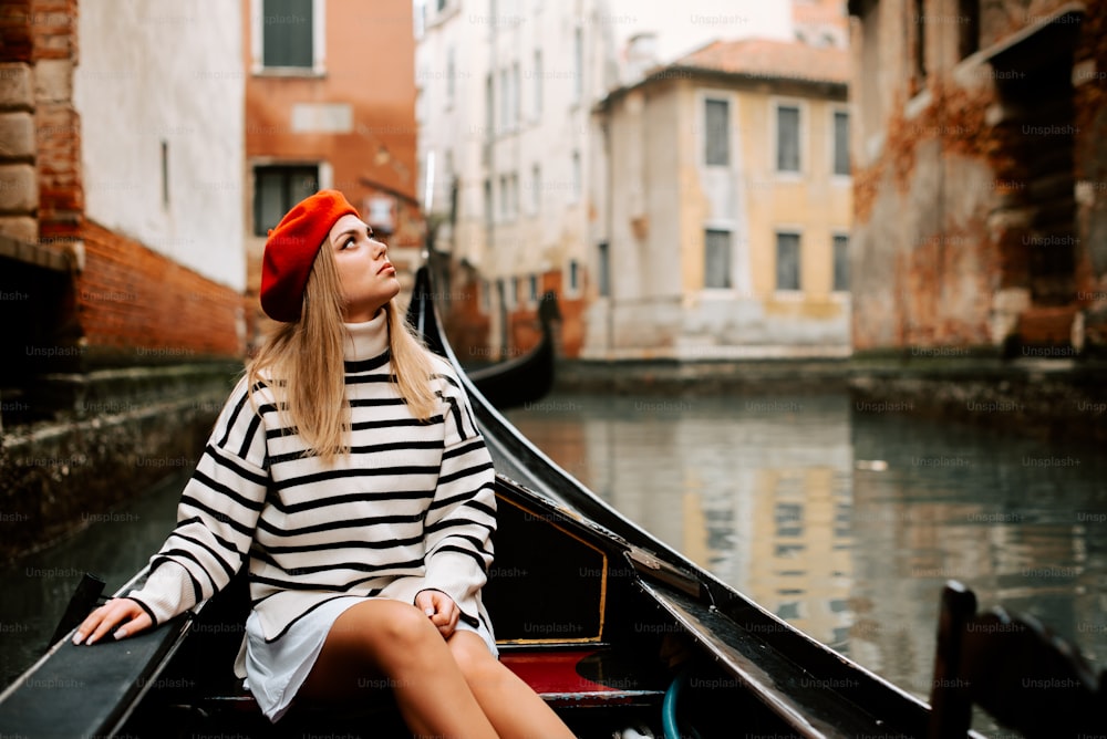 uma mulher sentada em um barco em um canal