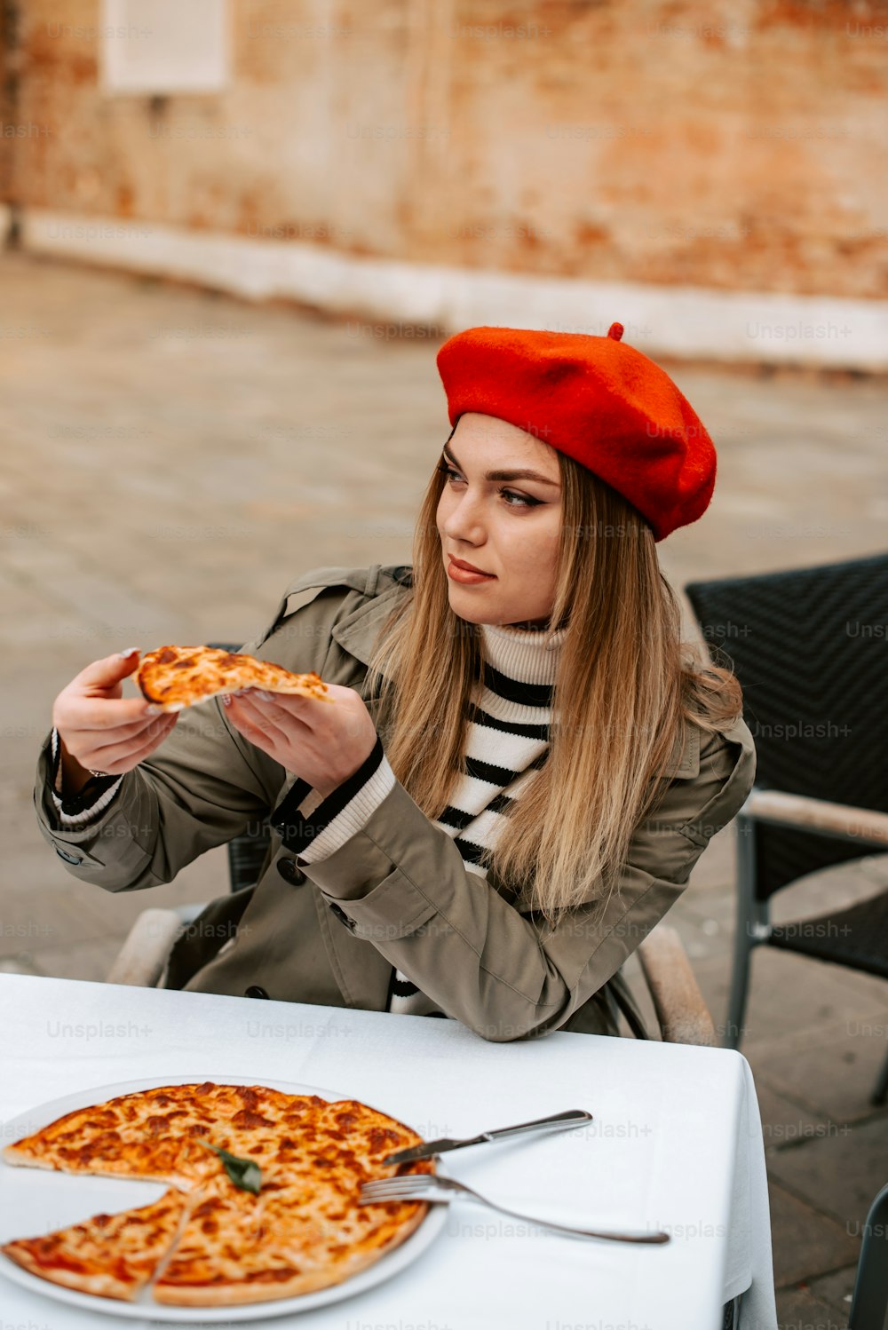 a woman sitting at a table with a pizza in front of her