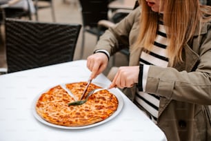 a woman cutting a pizza with a knife and fork
