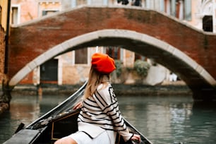a woman in a red hat is sitting in a boat